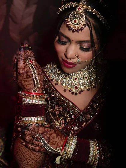 A close-up focusing on the bride's hands, adorned with intricate jewelry and henna, as she adjusts her bangles. It's a celebration of bridal details.