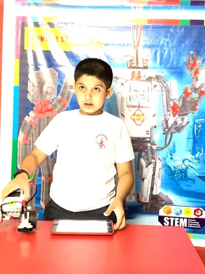 A young participant in our robotics competition stands by his creation, a programmable vehicle built with a LEGO robotics kit.