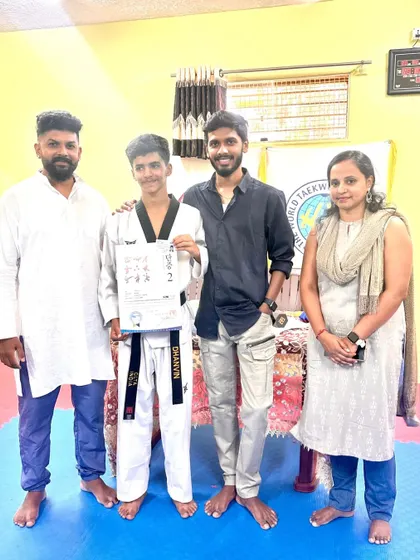 A student proudly holds his black belt certificate with his family.