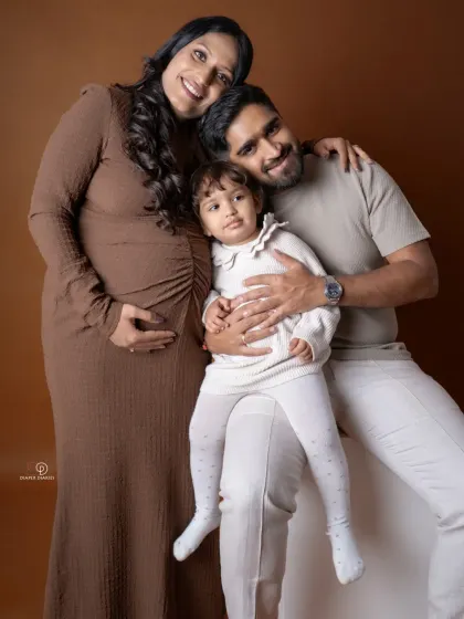 A classic family portrait against a warm, earthy backdrop. This photo beautifully captures the love and connection as this family of three prepares to become four.