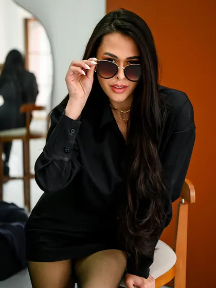 A crisp, clear version of the sunglasses portrait, focusing on the direct, confident gaze and the sleek styling of the all-black look.