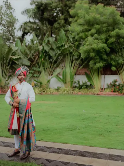A full-length portrait of the groom looking directly at the camera. This shot showcases the elegance and pride of the traditional 'navardev' look.