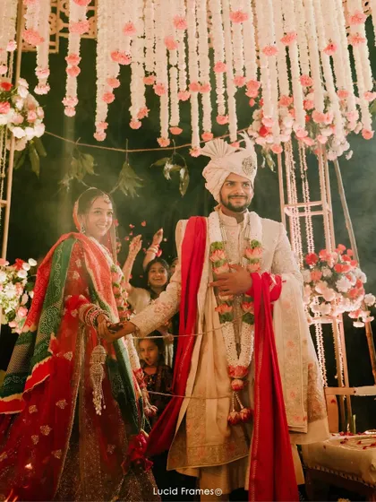 The couple holds hands at their mandap, a beautiful moment from their nighttime wedding ceremony.