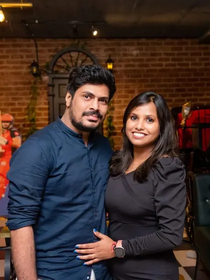 A couple posing for a picture inside the pub. You can see the cricket-themed decor in the background, which adds to the sporty and fun atmosphere of the place.