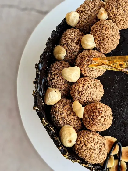 An overhead view of the Ferrero Rocher cake, showing the generous topping of homemade chocolate truffles and whole hazelnuts.