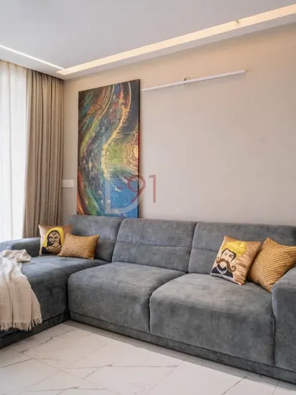 The living room is bathed in natural light, creating a bright and airy feel that complements the cool-toned furniture.