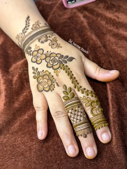 A delicate floral trail design for the back of the hand. The fresh green henna paste indicates the use of natural and high-quality ingredients for a great stain.