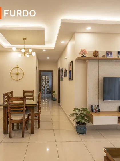 An open-plan layout showing the dining and living areas. The floating TV unit and minimalist furniture keep the space feeling open and uncluttered, while a modern chandelier defines the dining zone.