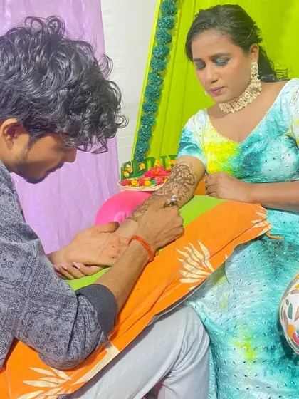 Applying mehandi for a client during what looks like a haldi or mehandi ceremony.
