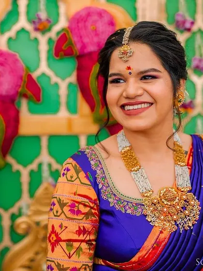 A radiant bride smiling, with a colorful and festive decor of parrots and flowers behind her. A shot full of joy and tradition.