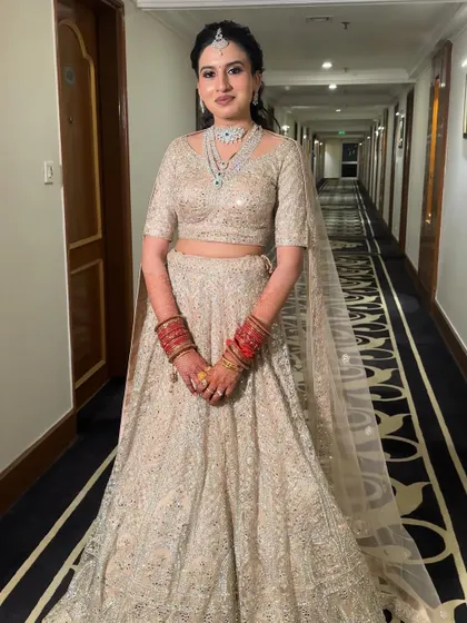 A full-length view of Damini's elegant reception outfit. The makeup was designed to be subtle yet impactful, complementing the intricate details of her lehenga without overpowering it.