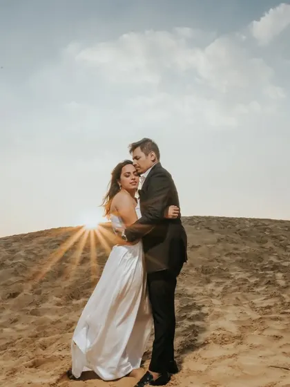 A romantic embrace on a sand dune at sunset. This destination shot uses the golden light and unique landscape to create a warm and dramatic pre-wedding portrait.