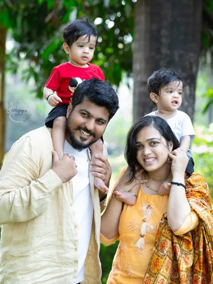 A beautiful family portrait taken outdoors, with happy parents giving their twin toddler sons a shoulder ride. This is what it's all about, capturing pure, unscripted joy.
