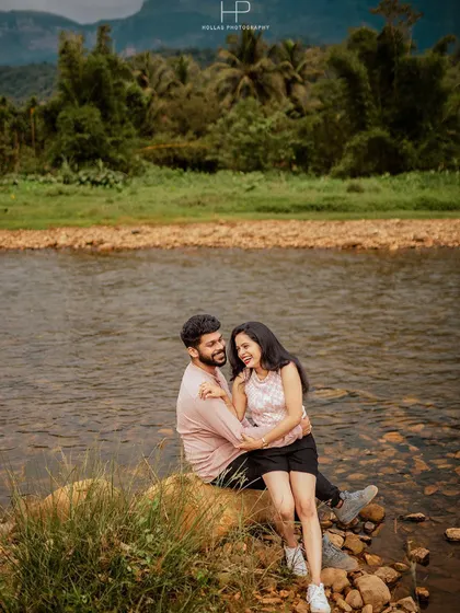 A happy, candid moment of a couple laughing together while sitting on a rock by a river. This shot perfectly captures the fun and relaxed vibe of an outdoor adventure shoot.