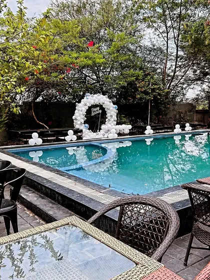 A poolside birthday decoration with a simple white balloon arch reflecting beautifully in the water.
