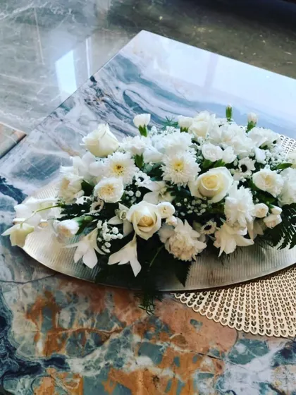 Even simple arrangements can be incredibly elegant. This low centerpiece of white roses and carnations on a silver platter is perfect for home events, dining tables, or as a subtle decorative accent.
