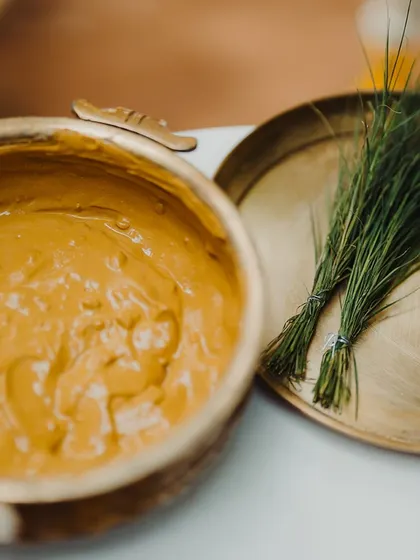 A brass bowl of freshly made turmeric paste and other items prepared for a traditional Haldi ceremony.