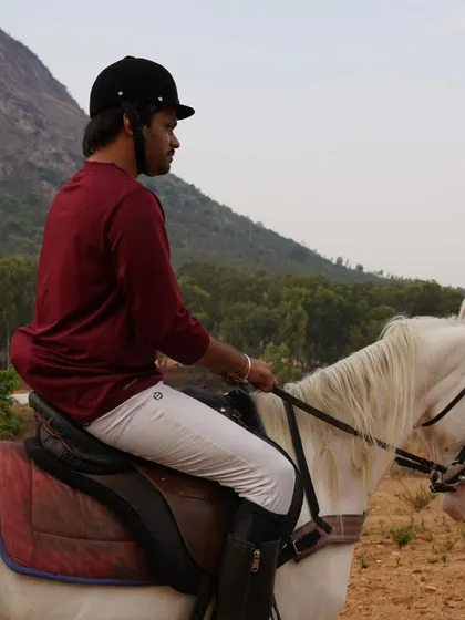 A rider looking back from his white horse on the trail. The bond between our riders and horses is clear in these moments.