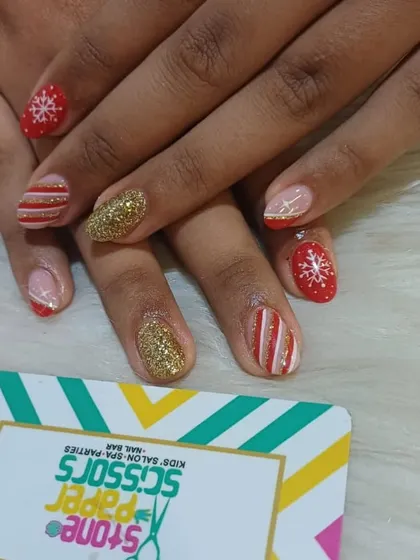 Getting into the festive spirit with this Christmas-themed nail art. The set includes hand-painted snowflakes, candy cane stripes, and a full-coverage gold glitter nail.