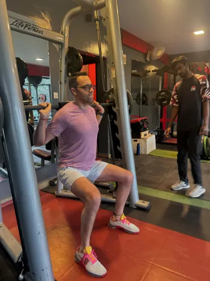 A coach provides verbal cues during a barbell squat. This personalized attention ensures every repetition is safe and effective, helping the client master the movement and build lower body power.