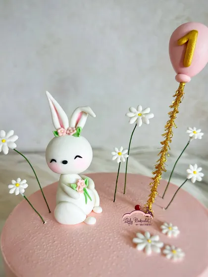 A close-up of the adorable, hand-sculpted bunny and the delicate daisy details.