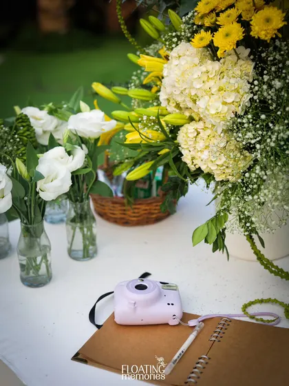 A detail of the Polaroid guest book station, where a simple camera and notebook become a cherished keepsake. The surrounding fresh flowers make it an inviting and beautiful corner.