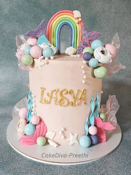 This super tall, 10-inch double-barrel cake combines two popular themes: mermaids and rainbows. It's a whimsical design with colorful chocolate spheres, fondant sea plants, and rice paper sails.