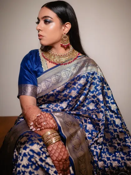 A seated portrait of Sonia, showcasing the rich texture of her saree and the bold makeup.
