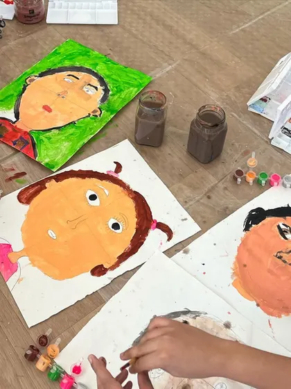 A table full of unique self-portraits painted by children. This powerful activity helps children explore their own identity and appreciate the unique features of their friends.