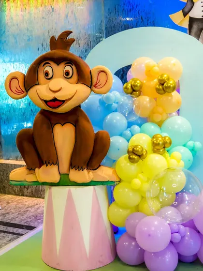 A cute monkey prop sitting on a circus pedestal, part of the detailed animal decorations for a carnival party.