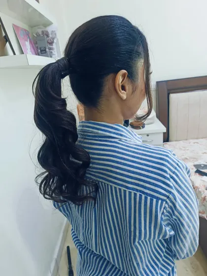 A classic high ponytail with curled ends and face-framing tendrils. This is a versatile and youthful style for any party or event.