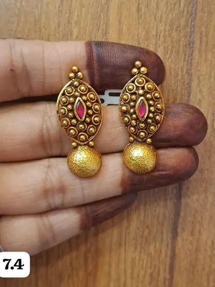 A lovely pair of oval-shaped antique silver earrings with gold plating. The design includes a ruby-colored stone and a textured gold drop, making them a unique accessory.