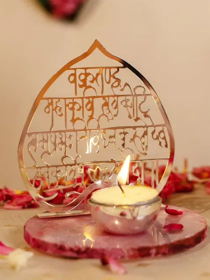 Sacred light, divine vibes. This elegant tea light holder, featuring the Vakratunda Mahakaya mantra beautifully carved in metal, sits on a rose quartz base, creating a serene and spiritual ambiance.