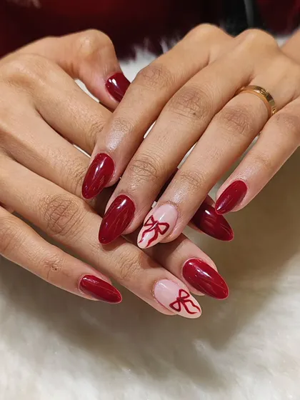 A closer look at the red bow nail art, showing the clean lines and glossy finish.