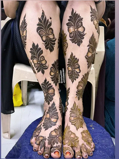 Another view of the unique bow-themed leg henna. The contrast between the dark paste and the skin is striking.