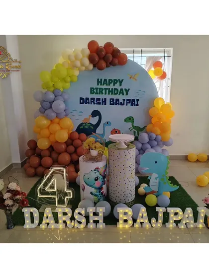 A cute dinosaur-themed party for a 4th birthday, with a custom backdrop, dino props, and marquee letters.