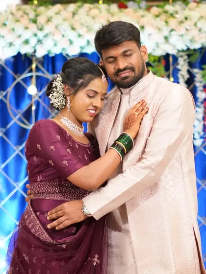 A happy couple enjoying their event. The backdrop features a floral border and blue drapes, creating a simple yet elegant setting.