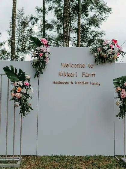 A modern and minimalist welcome backdrop designed for an event at Kikkeri Farm. The clean white wall was accented with asymmetrical floral arrangements, creating a chic and stylish photo opportunity for arriving guests.