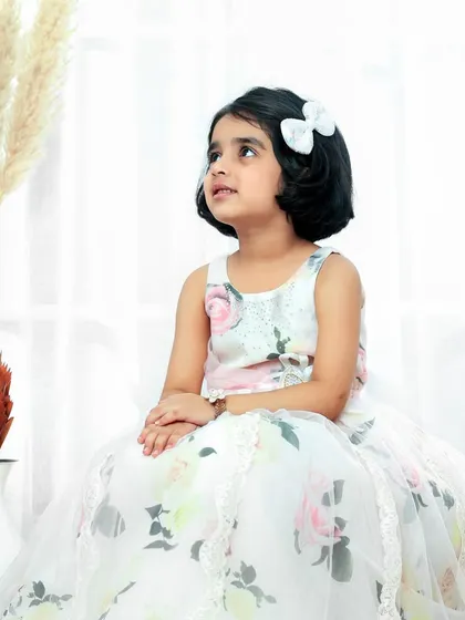 A thoughtful moment from a little princess. Dressed in a beautiful floral gown, she looks like she's dreaming of her fairy tale castle.