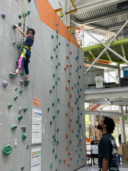 A young girl enjoys her climb, watched closely by her belayer. It's a great activity for building trust and communication skills.