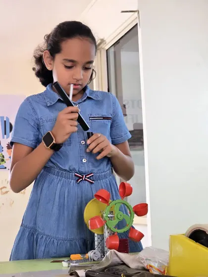 A student works on her water turbine model, a project that teaches the fundamentals of renewable energy and mechanical engineering.