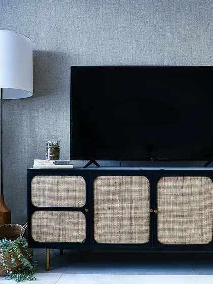 A close-up of the bespoke TV console, showcasing the beautiful texture of the natural cane panels against the dark wood frame, a perfect example of modern craftsmanship.