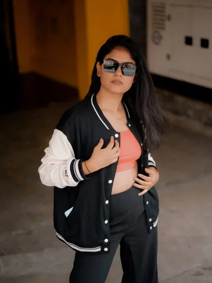 A portrait of a model in a varsity jacket, looking over her shoulder. The urban setting and her cool demeanor create a stylish and confident shot.