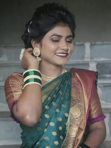 A happy Maharashtrian client ready for her function. The makeup is fresh and radiant, paired with a classic bun hairstyle and gold jewelry.
