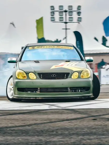 A custom Lexus drift car going sideways, tires smoking, in front of the packed spectator area. We bring in top drifters to put on a world-class show.