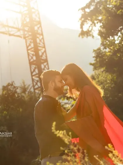 A golden hour pre-wedding portrait with the sun creating a beautiful flare behind the couple. This kind of lighting adds a dreamy and romantic quality to the photograph.