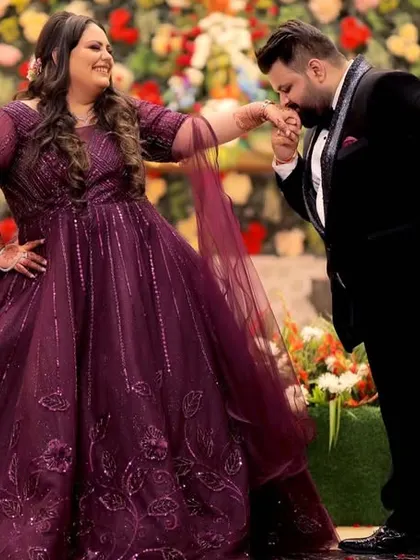 A charming and classic pose with the groom kissing the bride's hand, set against a beautiful floral backdrop at their engagement party.