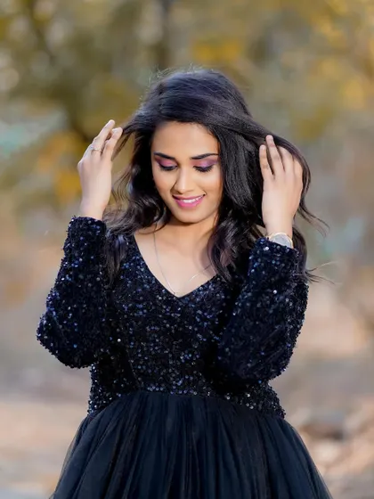 A candid moment of her fixing her hair. The makeup, especially the dramatic eye, looks stunning even in a relaxed, unposed shot.