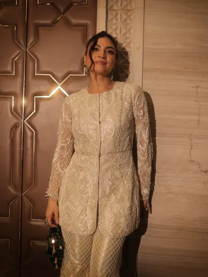 Step into the spotlight with flawless glam. This look is powerful and chic, with a clean top knot and subtle makeup that lets the intricate white outfit shine.