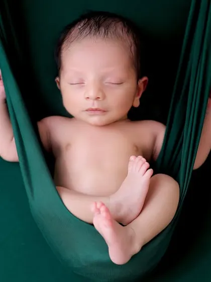 The 'hanging pose' is achieved using composite photography to ensure the baby is safe at all times. The baby is supported on a surface, and the prop is edited in later.